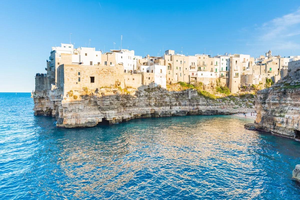 La cala di Polignano a Mare con l'acqua chiara ai piedi del borgo