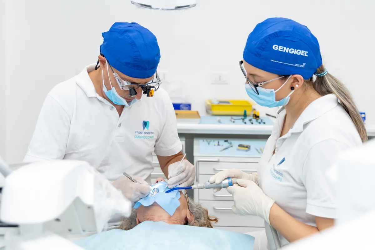 Il dentista e l'assistente durante una cura con la diga di gomma