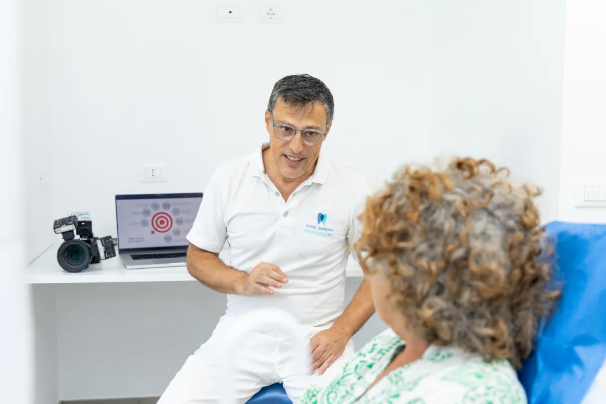 Il dentista parla con una paziente seduta in poltrona per metterla a suo agio prima della seduta