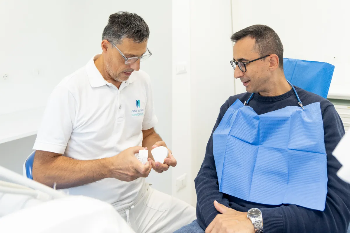 Il dentista mostra un modello dentale al paziente