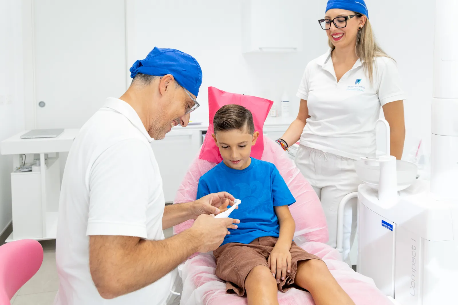 Il dentista spiega la visita a un ragazzo, con l'assistente accanto